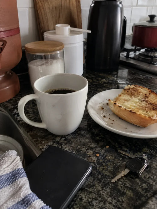 Café coado, pão na chapa e um pote de suplemento esquecido na bancada