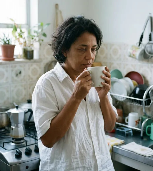 Mulher tomando café na cozinha de manhã